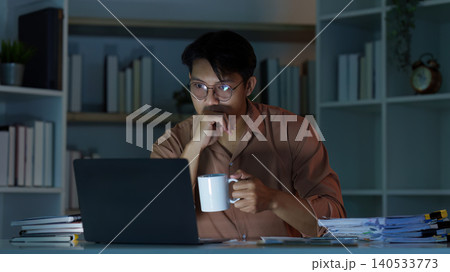 Asian man focused on remote work and productivity at home office at night 140533773