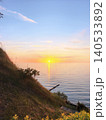 Sun setting over calm sea from hillside 140533892