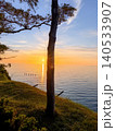 Tree silhouette at sunset over calm sea 140533907