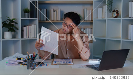 Asian man in his 20s stressed by financial documents at home office Asian man in his 20s stressed by financial documents at home office 140533935