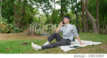 Asian man talking on phone call outdoors in park for remote communication 140533967
