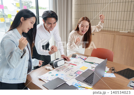 Asian UX UI design team celebrating app development success in office 140534023