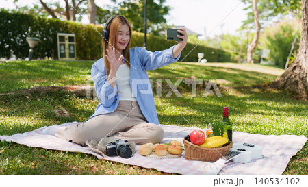 Asian woman making video call with smartphone in outdoor park for social connection Asian woman making video call with smartphone in outdoor park for social connection 140534102