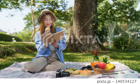 Asian woman enjoying picnic and reading book in park during spring leisure Asian woman enjoying picnic and reading book in park during spring leisure 140534127