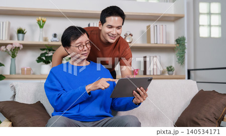 Asian senior man learning digital technology on tablet with younger man Asian senior man learning digital technology on tablet with younger man 140534171