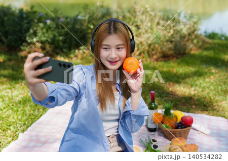 Asian woman in her 20s taking a social media selfie at an outdoor park picnic Asian woman in her 20s taking a social media selfie at an outdoor park picnic 140534282
