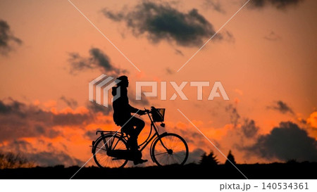 silhouette of cyclist with bike on the hill at sunset 140534361