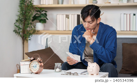 Asian man reviewing bills for budgeting, personal finance planning at home Asian man reviewing bills for budgeting, personal finance planning at home 140534396