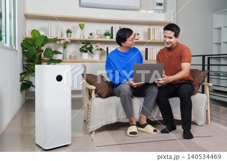 Asian senior man and young man using laptop with smart air purifier at home 140534469