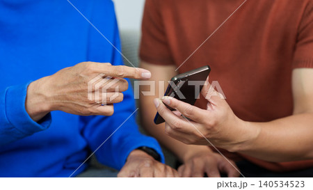Asian man teaching senior how to use smartphone, digital technology learning Asian man teaching senior how to use smartphone, digital technology learning 140534523