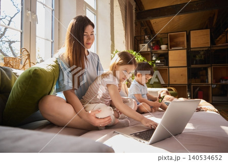 Mother and daughter smiling while using laptop together on sofa at home. Mother and daughter smiling while using laptop together on sofa at home. 140534652