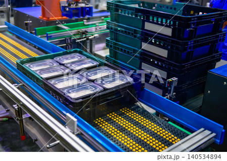 Modern automated food production line sorting ready to eat meal trays into industrial plastic baskets	 140534894
