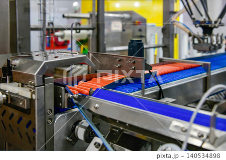 Modern industrial hot dog production machinery processing fresh sausages on automated conveyor line 140534898
