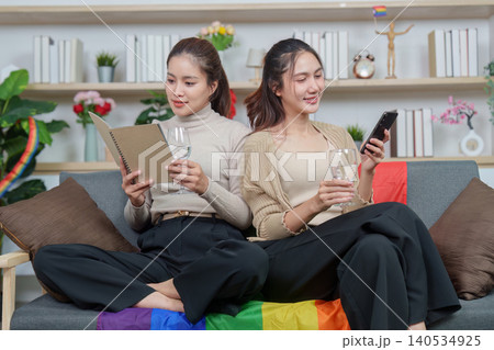 Asian lesbian couple relaxing on sofa at home, modern LGBTQ relationship Asian lesbian couple relaxing on sofa at home, modern LGBTQ relationship 140534925