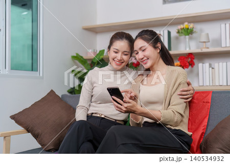 Asian LGBTQ couple sharing happy smartphone moment at home 140534932