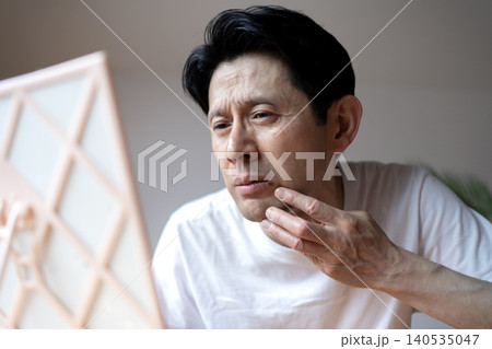 鏡を見ながら口元にできた口唇ヘルペスの症状に悩み、顔をしかめるミドル男性 鏡を見ながら口元にできた口唇ヘルペスの症状に悩み、顔をしかめるミドル男性 140535047