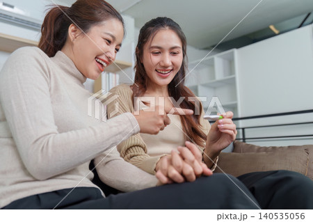 Asian LGBTQ women couple excited with positive pregnancy test result Asian LGBTQ women couple excited with positive pregnancy test result 140535056