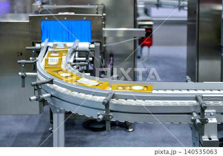 Industrial x-ray inspection system scanning food product packages on curved conveyor belt Industrial x-ray inspection system scanning food product packages on curved conveyor belt 140535063
