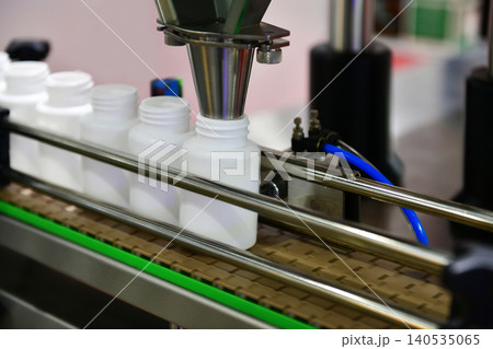 Automatic white plastic bottle filling machine working on conveyor belt line in pharmaceutical factory 140535065