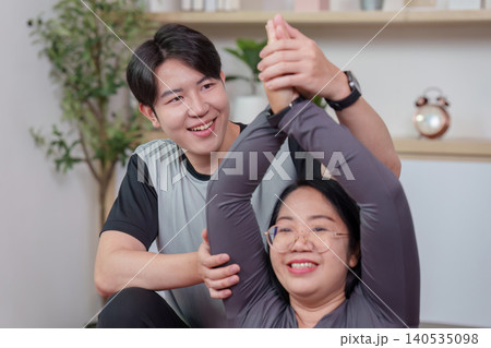 Asian man training woman stretching at home, wellness fitness Asian man training woman stretching at home, wellness fitness 140535098