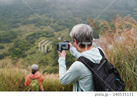 Senior Hiker Photographs Misty Yangmingshan Valley with Smartphone Senior Hiker Photographs Misty Yangmingshan Valley with Smartphone 140535131
