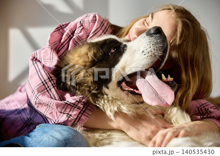 Young woman hugging Saint Bernard dog close up emotional support pet lifestyle. 140535430