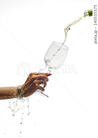 White wine splashing from glass while pouring isolated on white background White wine splashing from glass while pouring isolated on white background 140535575