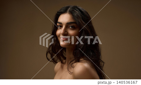 Brunette woman smiling with natural wavy hair on warm brown beauty background. Brunette woman smiling with natural wavy hair on warm brown beauty background. 140536167