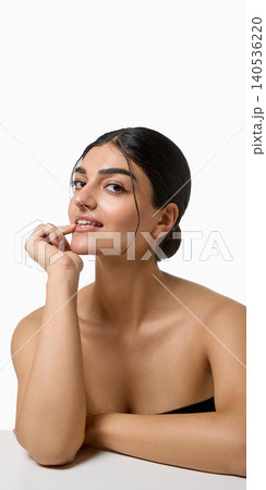 Smiling beauty model with glossy lips and hand near face on white background. 140536220