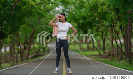 Smiling Black woman wiping sweat with towel after outdoor workout for healthy lifestyle 140536269