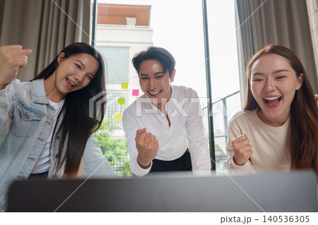 Excited Asian business team celebrating success at laptop in office 140536305