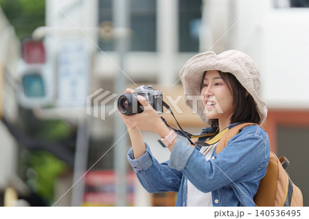 Happy Asian woman tourist taking photo with camera outdoors for travel photography and memory capture 140536495