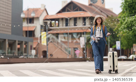 Asian woman traveling with suitcase and backpack exploring city for summer vacation tourism Asian woman traveling with suitcase and backpack exploring city for summer vacation tourism 140536539