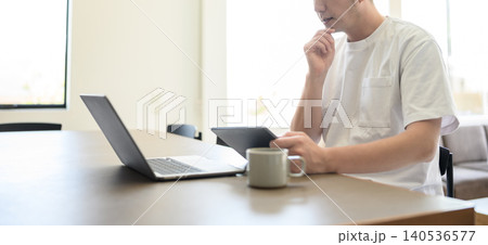 自宅でタブレットとPCを操作する男性 自宅でタブレットとPCを操作する男性 140536577