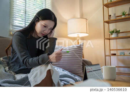 Asian woman looking at pregnancy test with worried expression at home for health 140536610