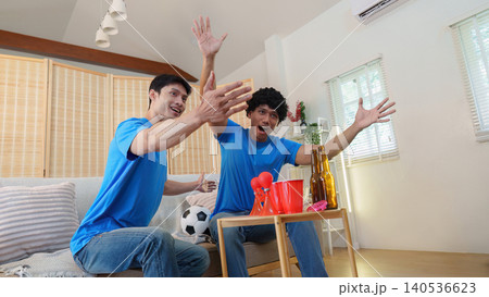 Asian men reacting with excitement to soccer game at home Asian men reacting with excitement to soccer game at home 140536623