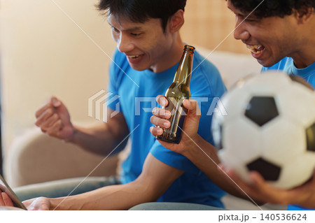 Asian men watching soccer game and celebrating with beer at home Asian men watching soccer game and celebrating with beer at home 140536624