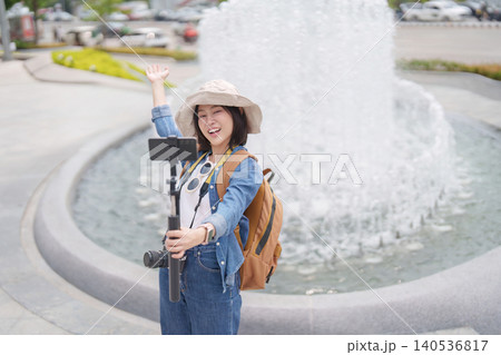 Asian woman vlogging with smartphone and camera outdoors 140536817