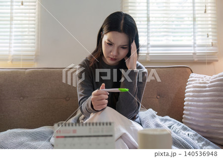 Asian woman looking at pregnancy test with worried expression at home Asian woman looking at pregnancy test with worried expression at home 140536948