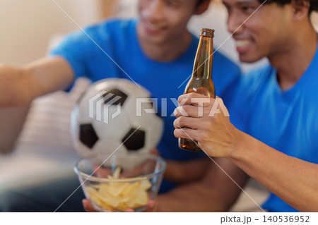 Asian men watching football game at home with beer and chips 140536952