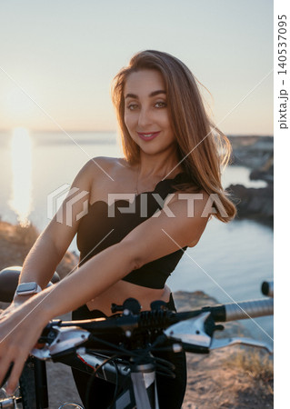 Woman bicycle sunset posing with mountain bike on a cliff overlooking the sea during golden hour for fitness and travel concept Woman bicycle sunset posing with mountain bike on a cliff overlooking the sea during golden hour for fitness and travel concept 140537095