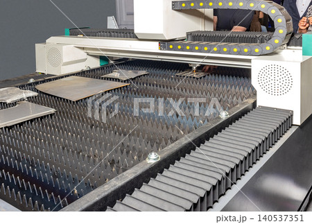 Laser cutting machine at work in a workshop during the day with workers completing metal cutting tasks Laser cutting machine at work in a workshop during the day with workers completing metal cutting tasks 140537351