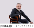 Serious mature bearded man sitting on chair and looking at camera 140537354