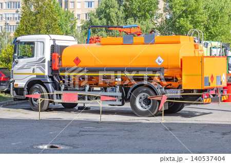 Truck with orange tank parked in a lot near buildings during daytime Truck with orange tank parked in a lot near buildings during daytime 140537404