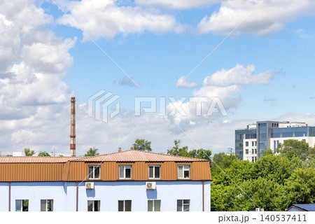 View of buildings under a cloudy sky with green trees in the background during daytime 140537411