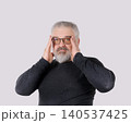 Mature bearded man adjusting eyeglasses and looking at camera isolated on gray background 140537425
