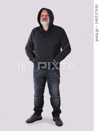 Mature bearded man in hoodie standing with hands in pockets Mature bearded man in hoodie standing with hands in pockets 140537430
