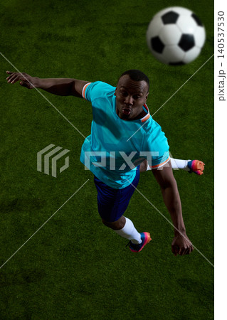 Overhead soccer player heading ball on green field with close action Overhead soccer player heading ball on green field with close action 140537530