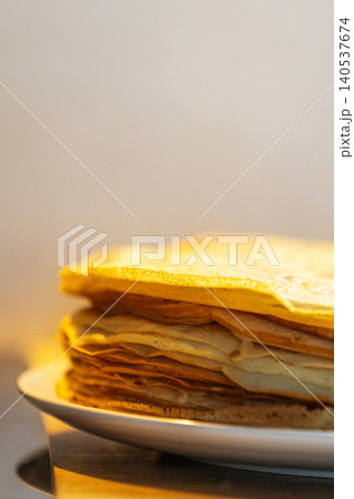 Stack of thin golden crepes on white plate Stack of thin golden crepes on white plate 140537674