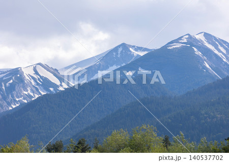 Snow-capped Pirin Mountains with dense evergreen forests and cloudy sky in Bansko, Bulgaria 140537702